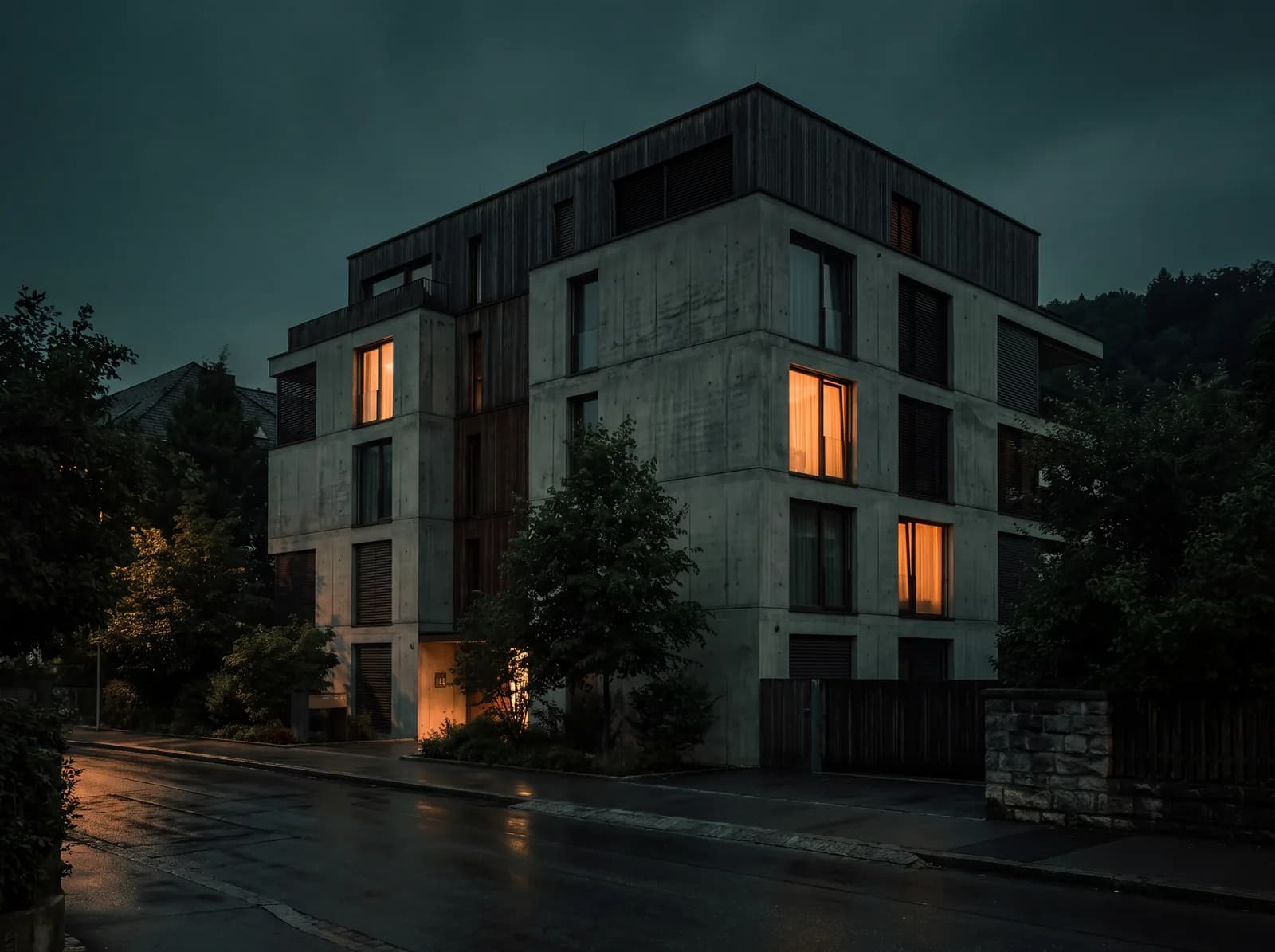 Mehrgeschossiges Wohnhaus in der Dämmerung, einzelne Fenster warm erleuchtet