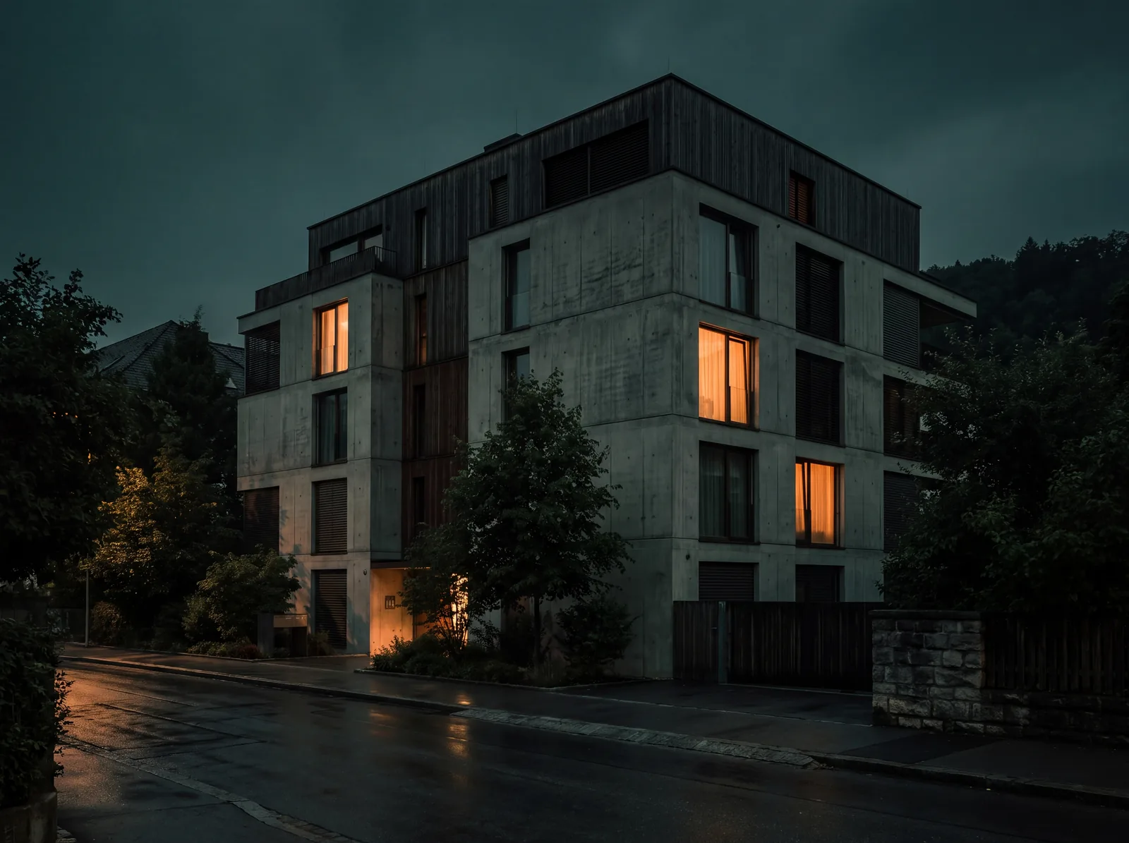 Mehrgeschossiges Wohnhaus in der Dämmerung, einzelne Fenster warm erleuchtet